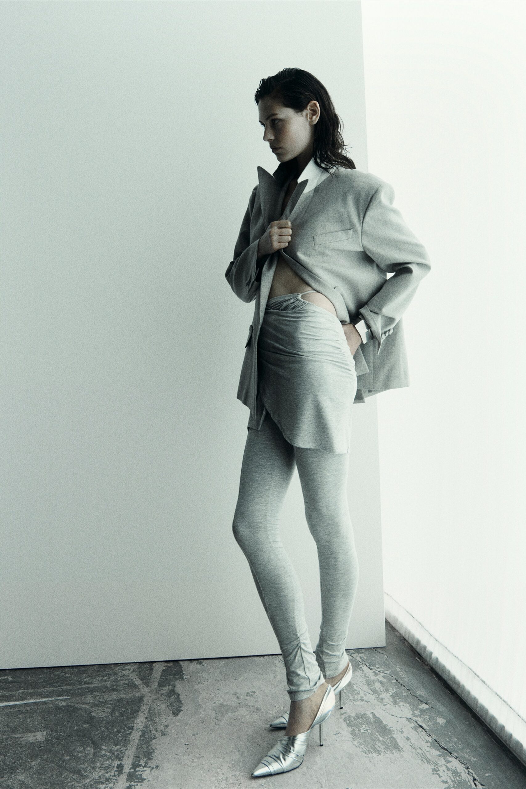 A fitted gray jacket with long sleeves paired with an asymmetric skirt.