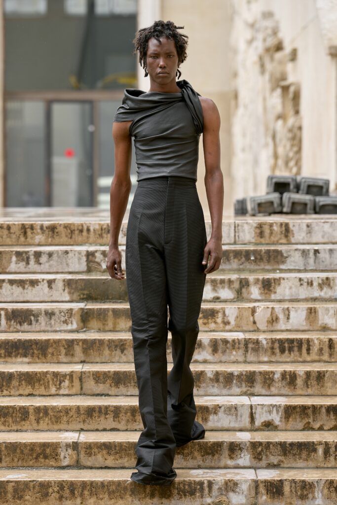 A fitted black sleeveless top with an asymmetric design paired with tailored black pants.