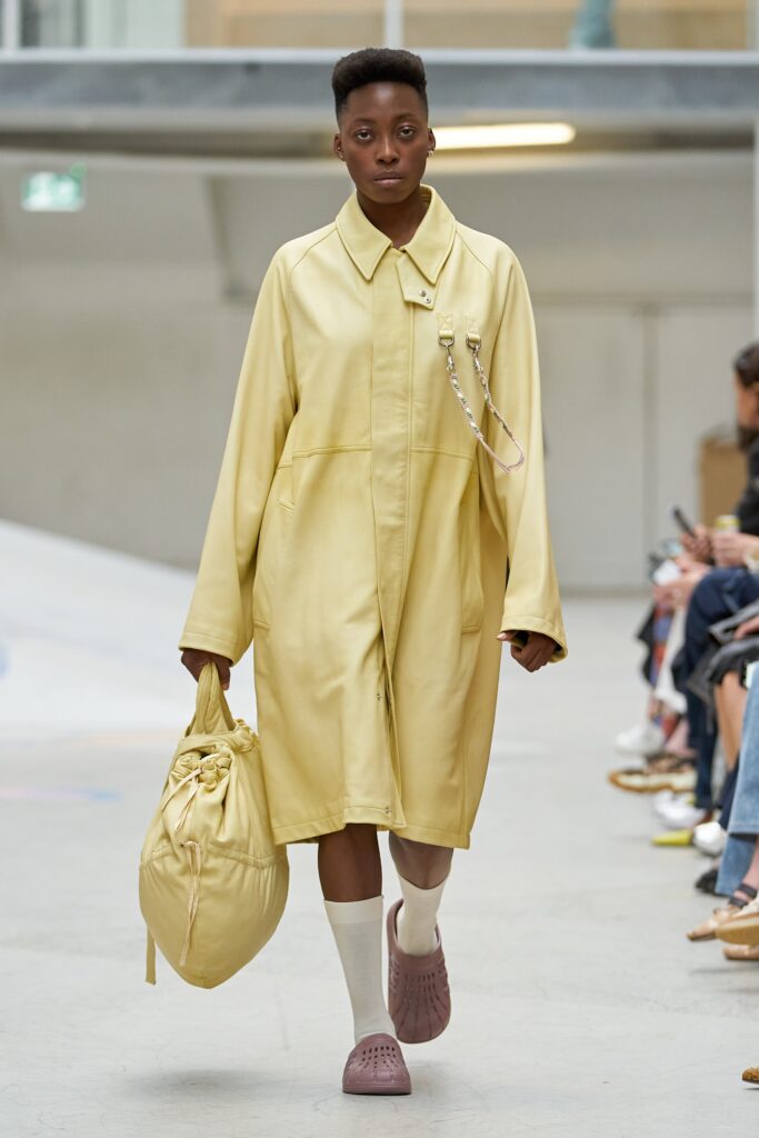 An oversized yellow cotton coat with long sleeves and a collared design featuring a zippered detail.