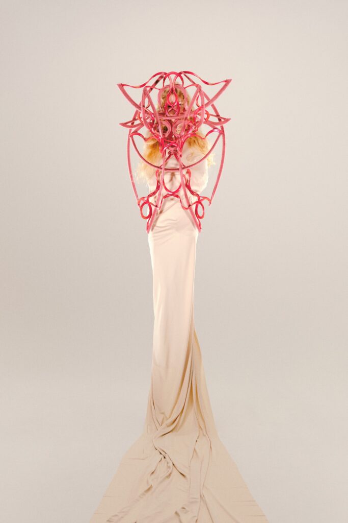 A fitted beige silk gown with intricate design details and long sleeves.