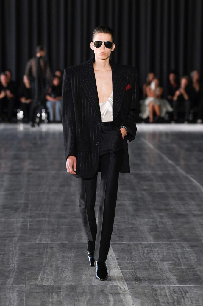 A tailored black striped blazer paired with matching pants, featuring a deep V-neckline.