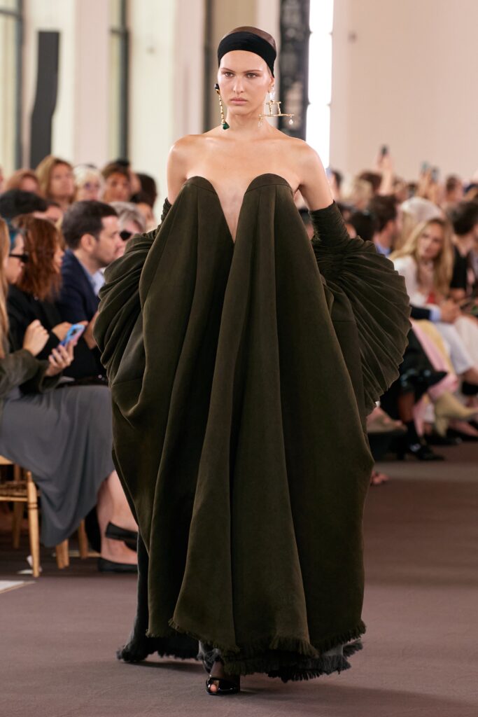 A relaxed green wool sleeveless dress with a high neckline and asymmetric design.
