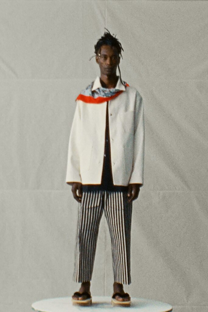 A relaxed white long-sleeve jacket paired with black and white striped pants.