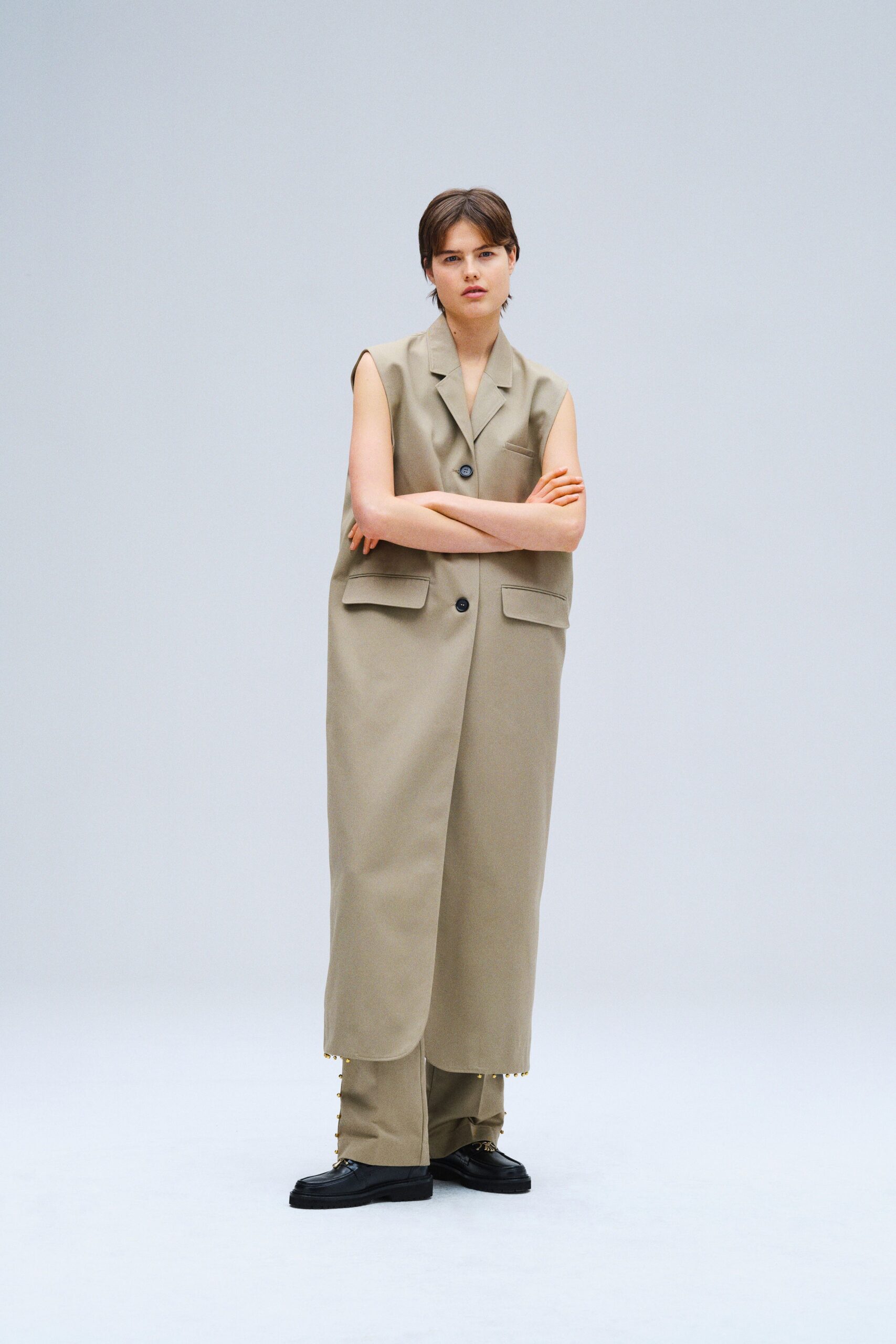 A relaxed beige cotton sleeveless vest with a collared design and button details.