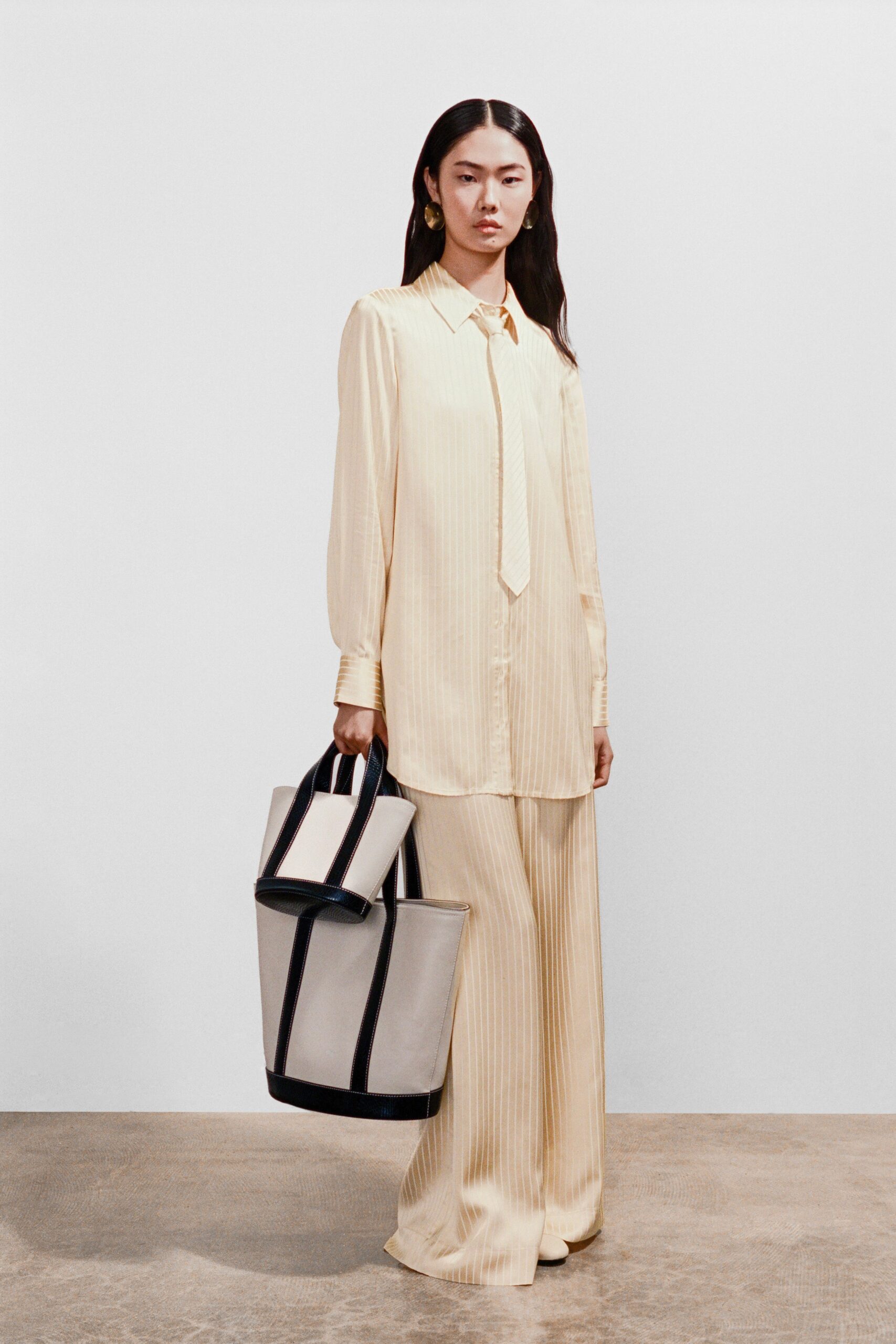 A relaxed cream long-sleeve collared shirt paired with striped pants.