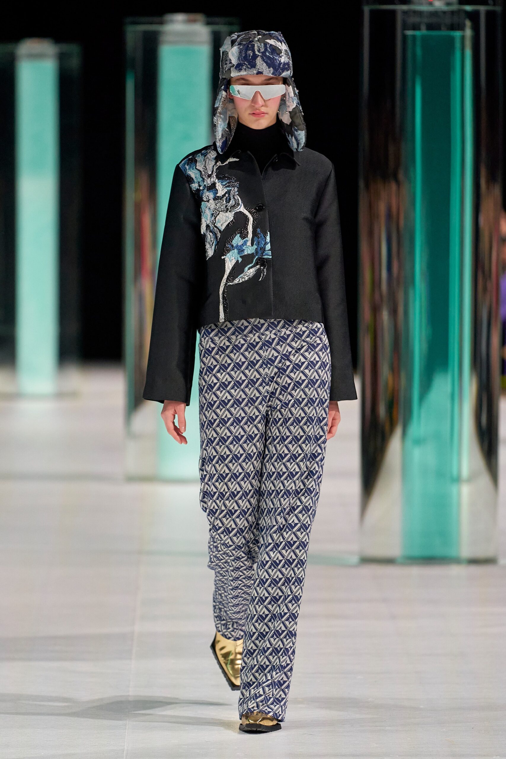A relaxed black jacket with a printed design paired with blue patterned pants.