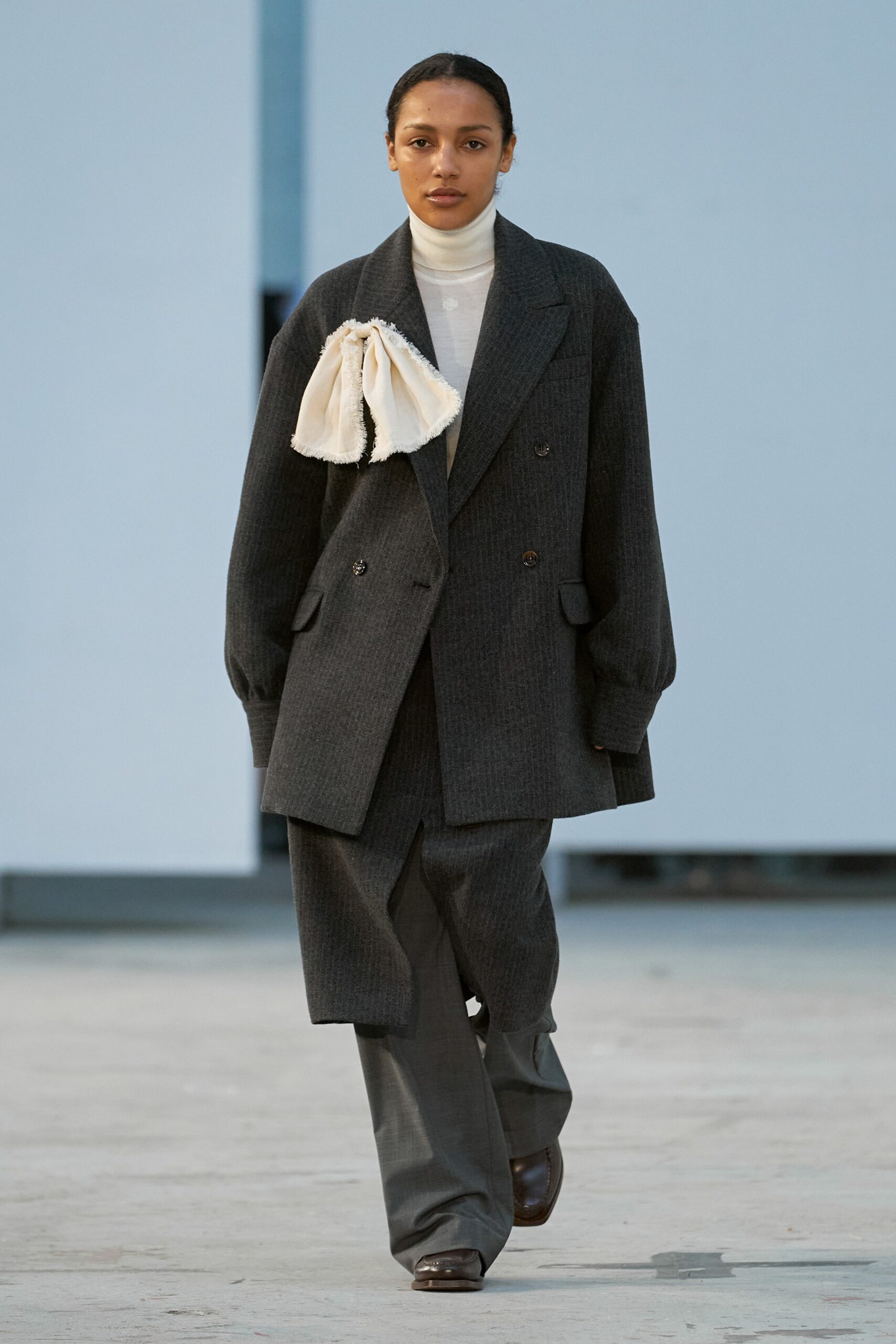 A relaxed gray wool coat with long sleeves and wide-leg pants, featuring a collared design.