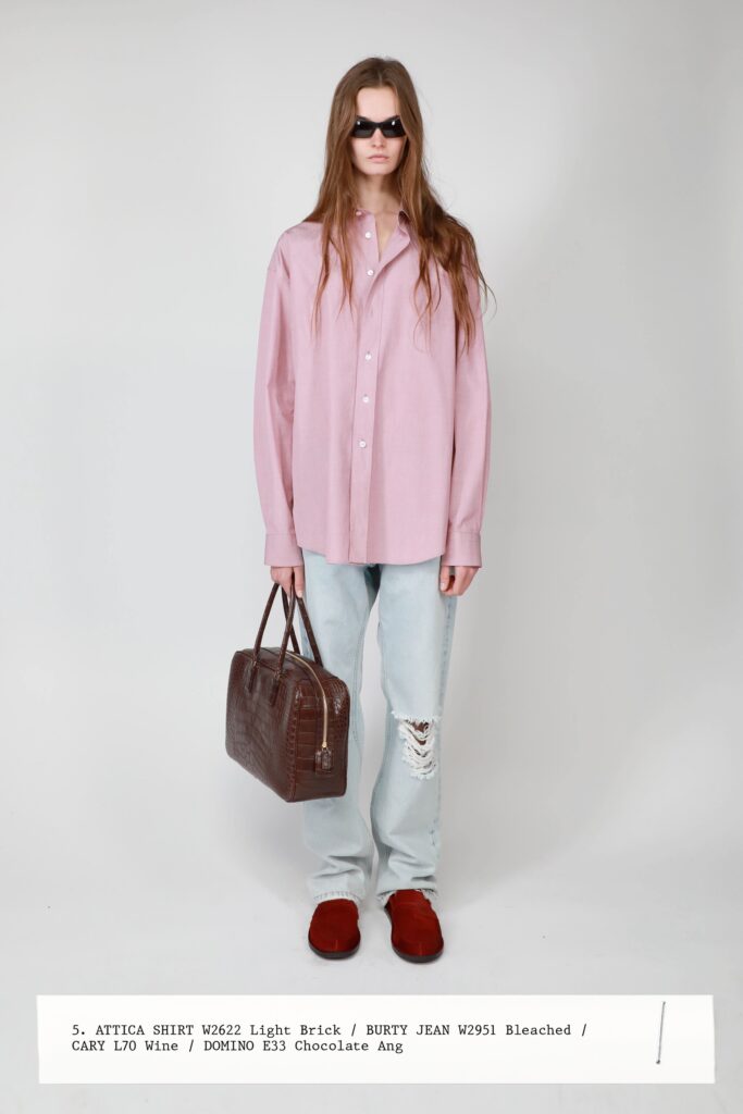 A relaxed pink long-sleeve collared shirt paired with distressed blue jeans.