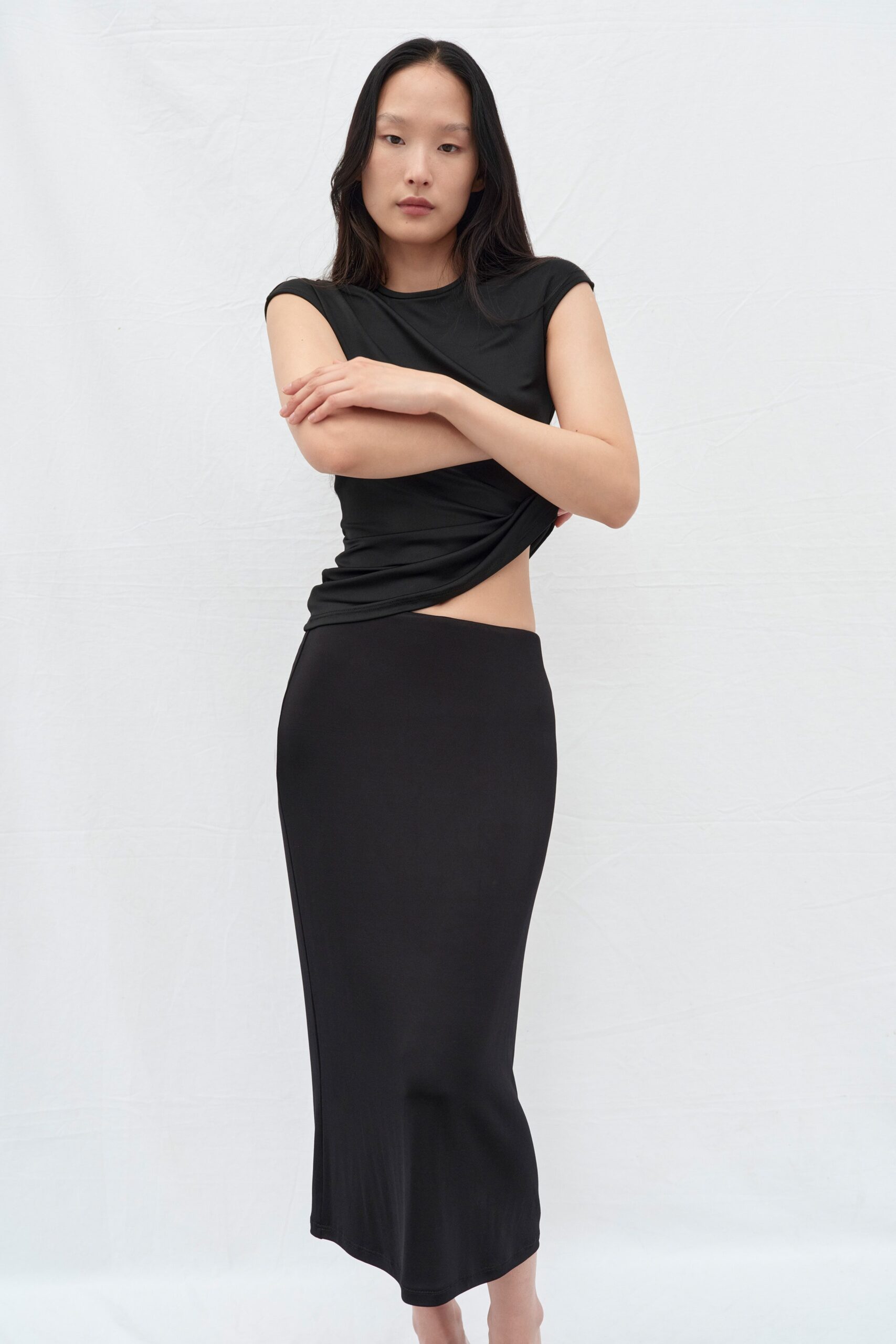 A fitted black top with short sleeves and a high-waisted asymmetric skirt.