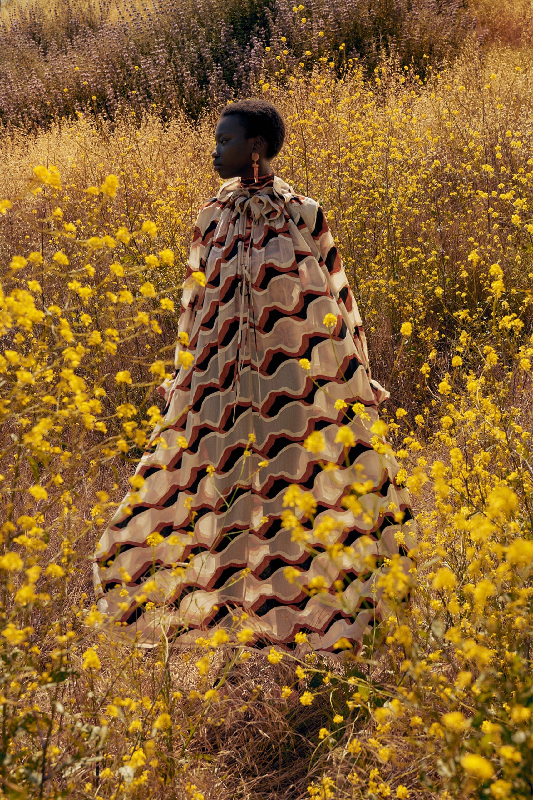 A relaxed beige printed silk cape dress with a high neckline and flowing silhouette.