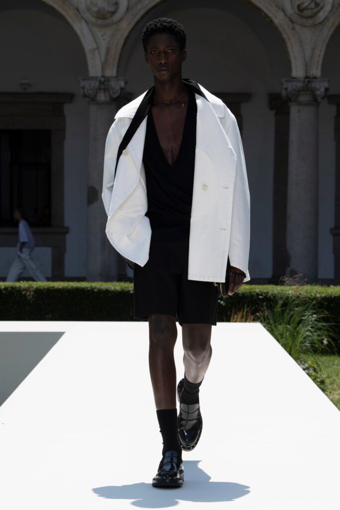 A relaxed white long-sleeve jacket paired with a v-neck top and black shorts.
