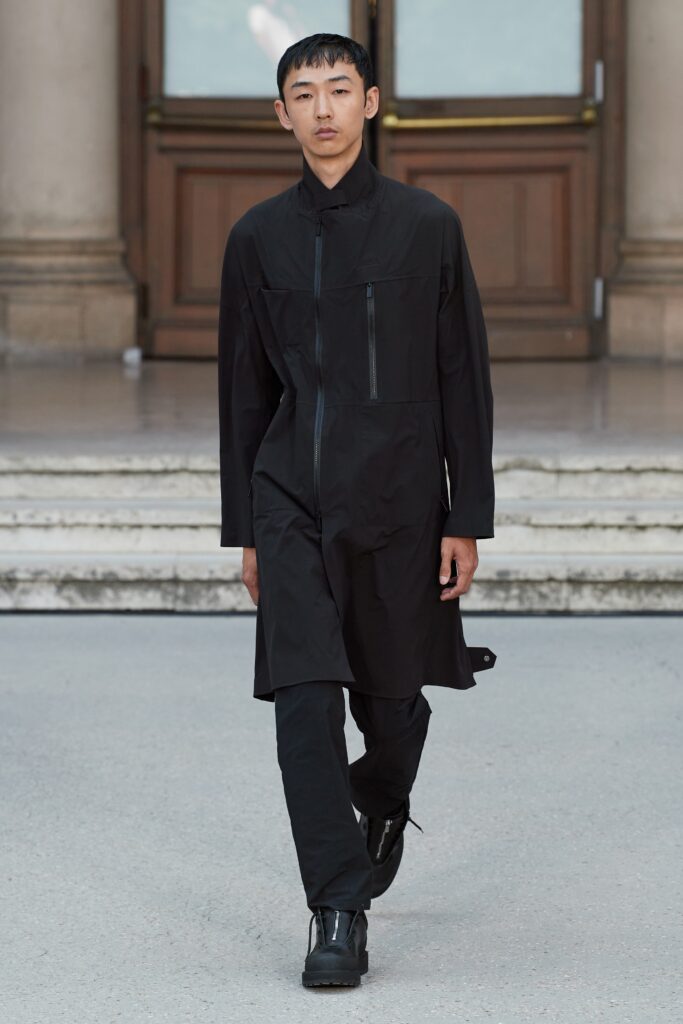 A relaxed black coat with long sleeves and a zippered front.