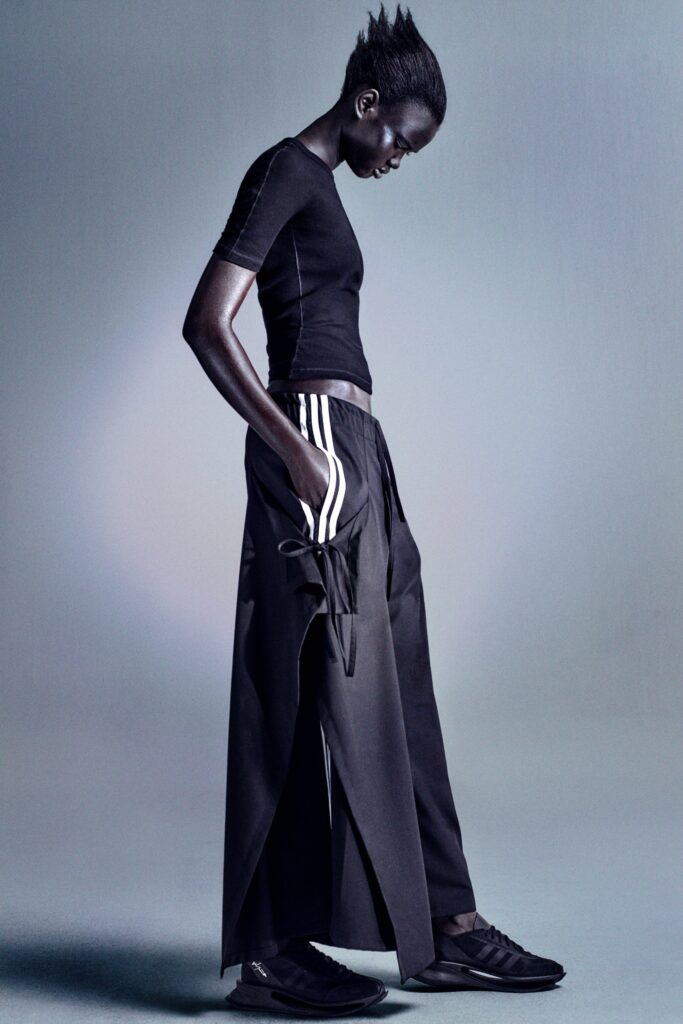 A fitted black top with short sleeves paired with high-waisted asymmetric pants.