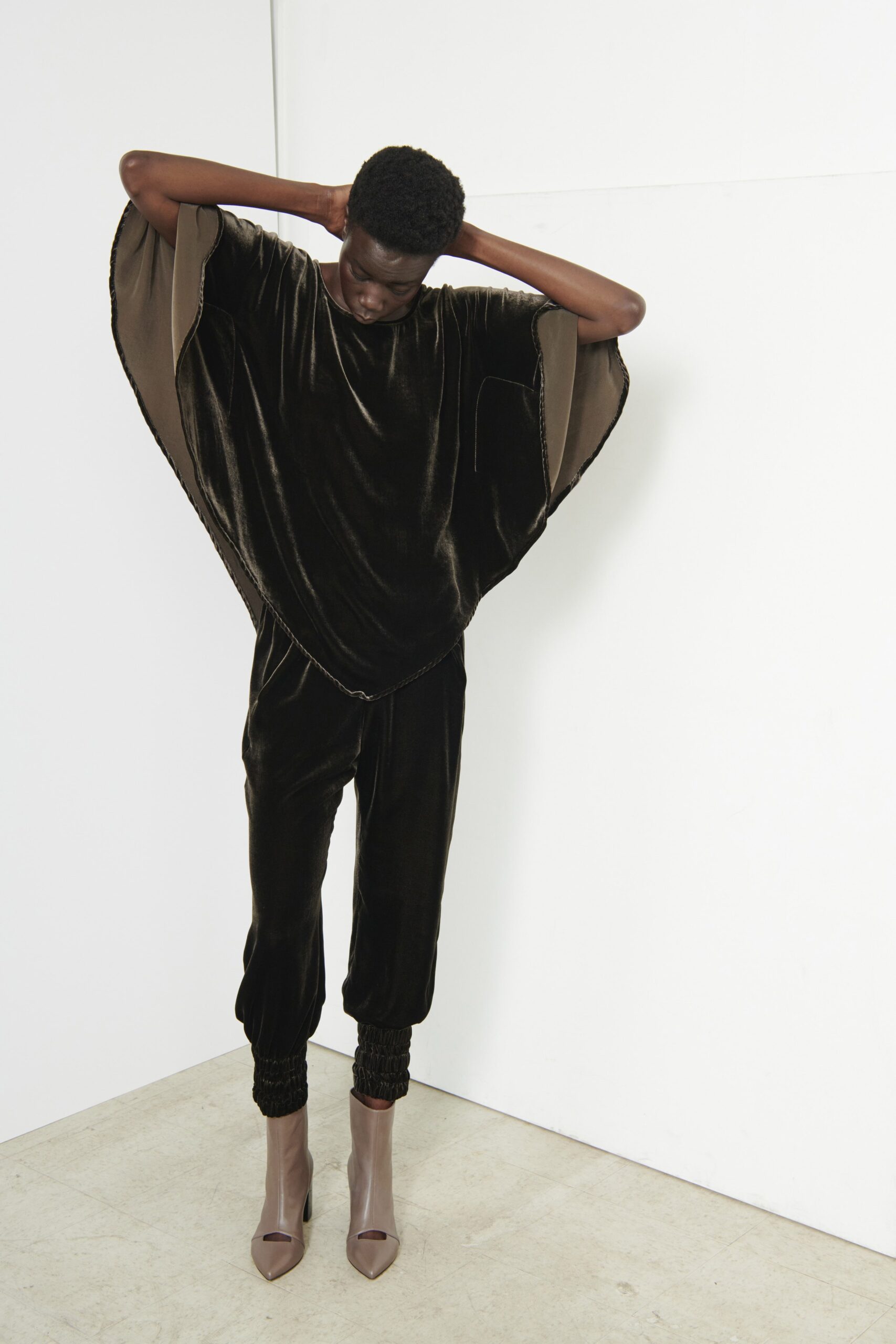 A relaxed black velvet jumpsuit with long sleeves and an asymmetric design detail.
