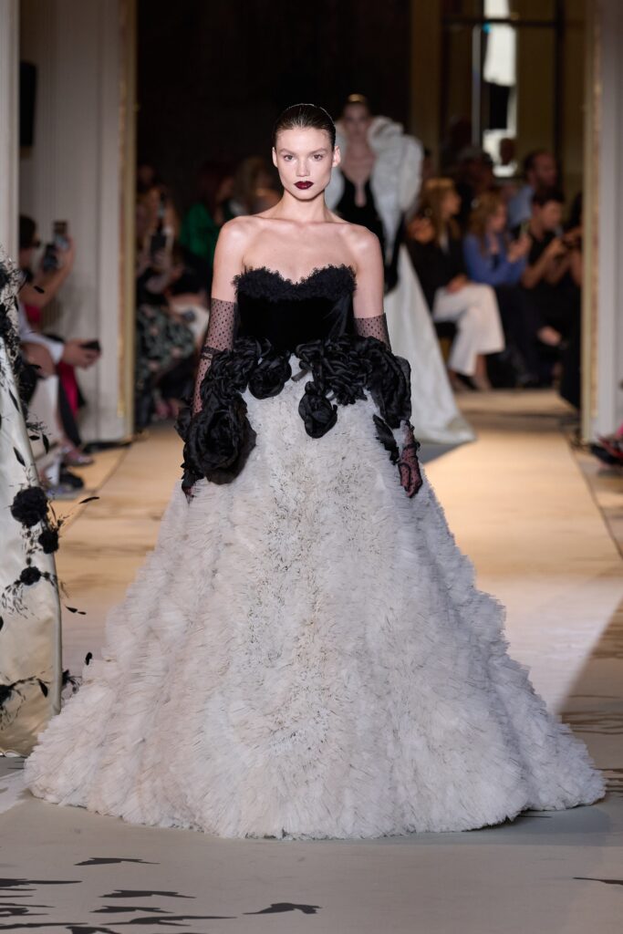 A fitted black and white gown with ruffled details and an off-shoulder design.