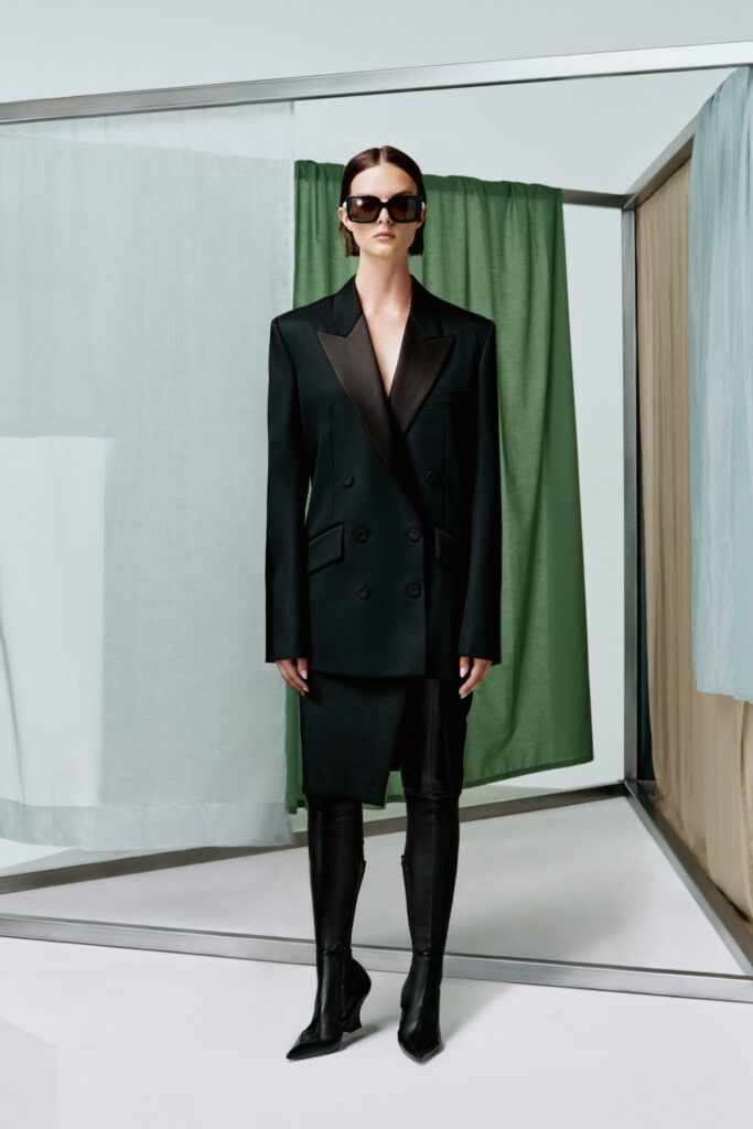A fitted black silk blazer with a V-neckline and an asymmetric skirt.