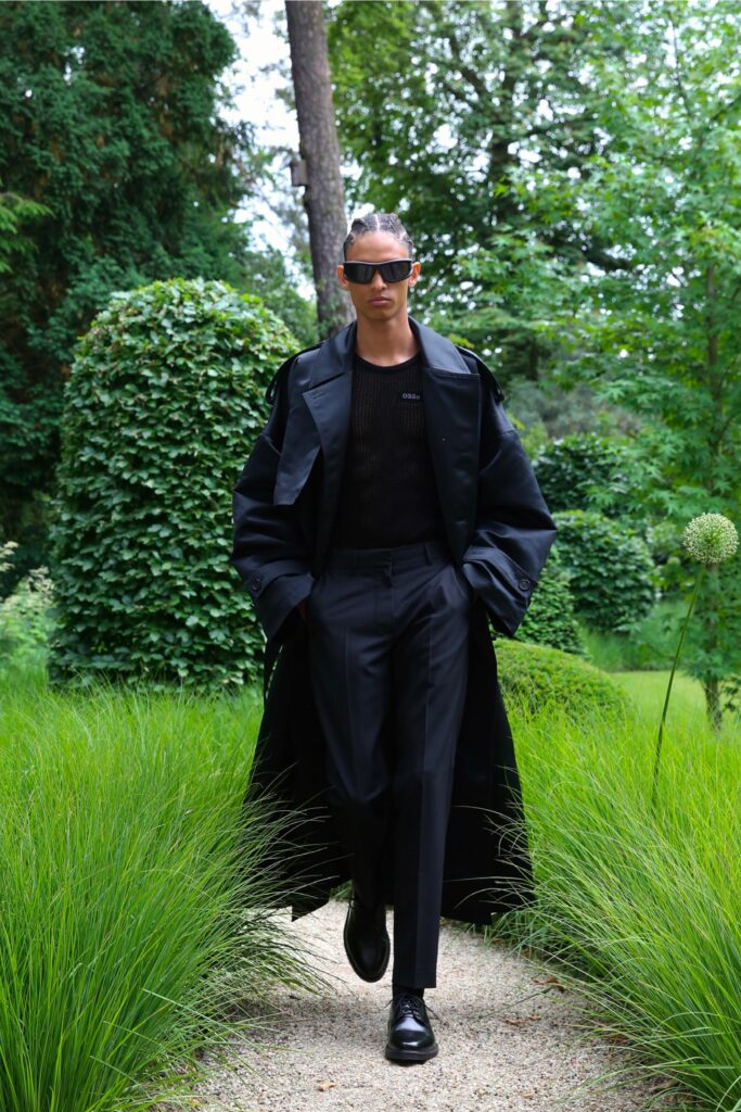 A fitted black coat layered over a black top and paired with tailored black pants.