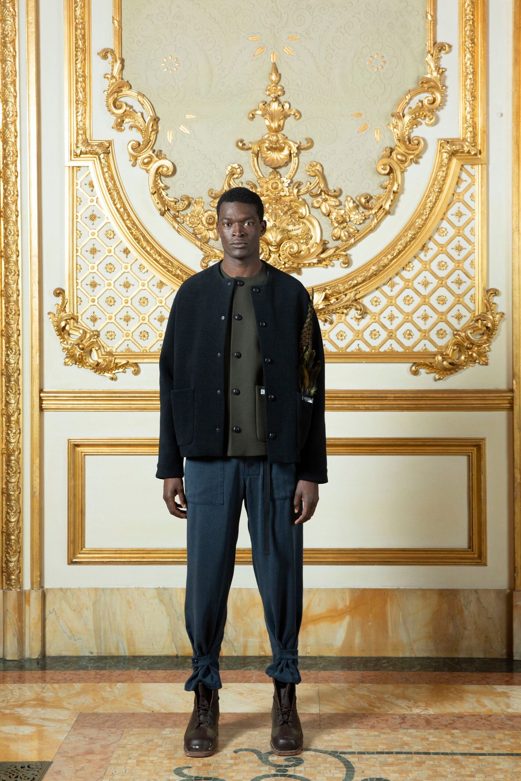 A relaxed black jacket with long sleeves paired with straight-leg blue pants.