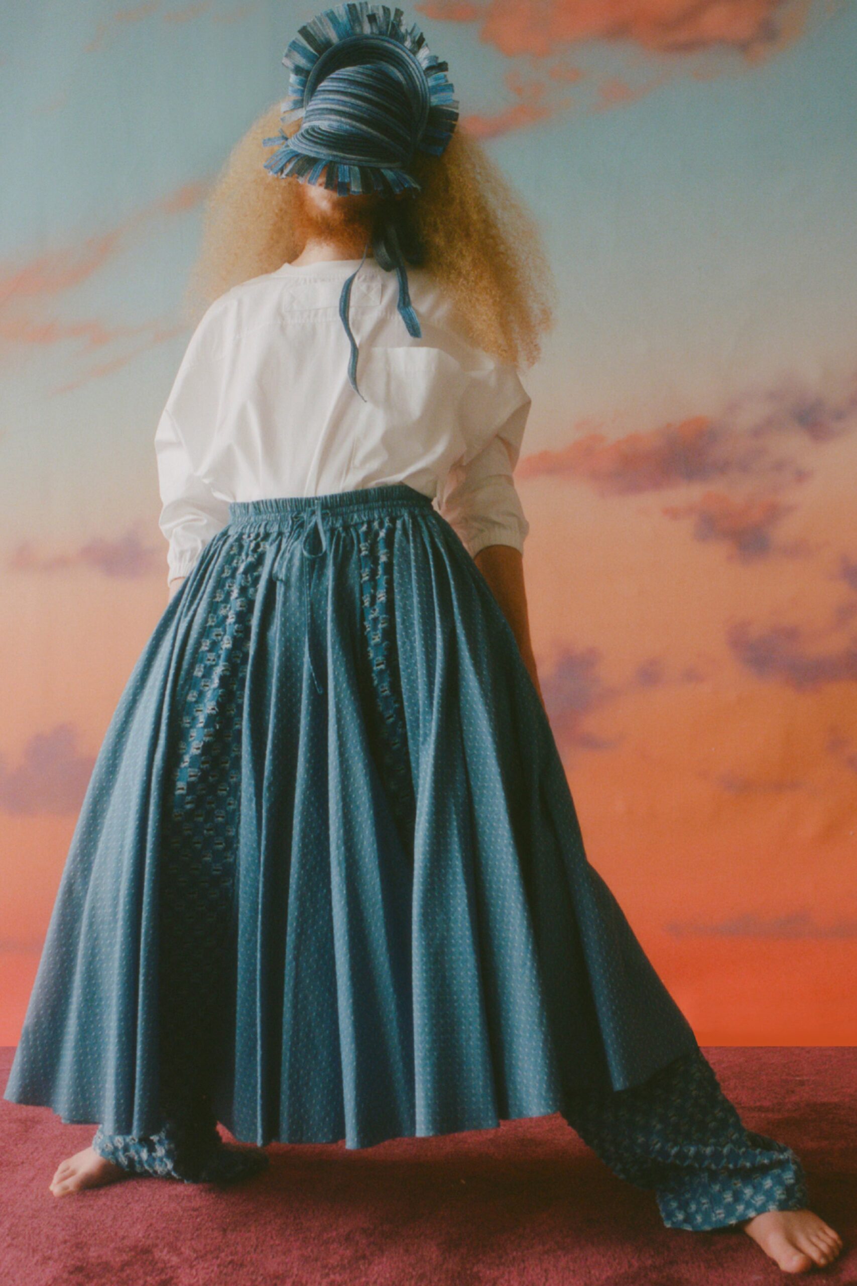 This ensemble features a relaxed long-sleeve shirt paired with a tiered pleated skirt, both in a striking blue hue. The combination creates a flowing silhouette that captures movement, while the pleats add texture and visual interest.