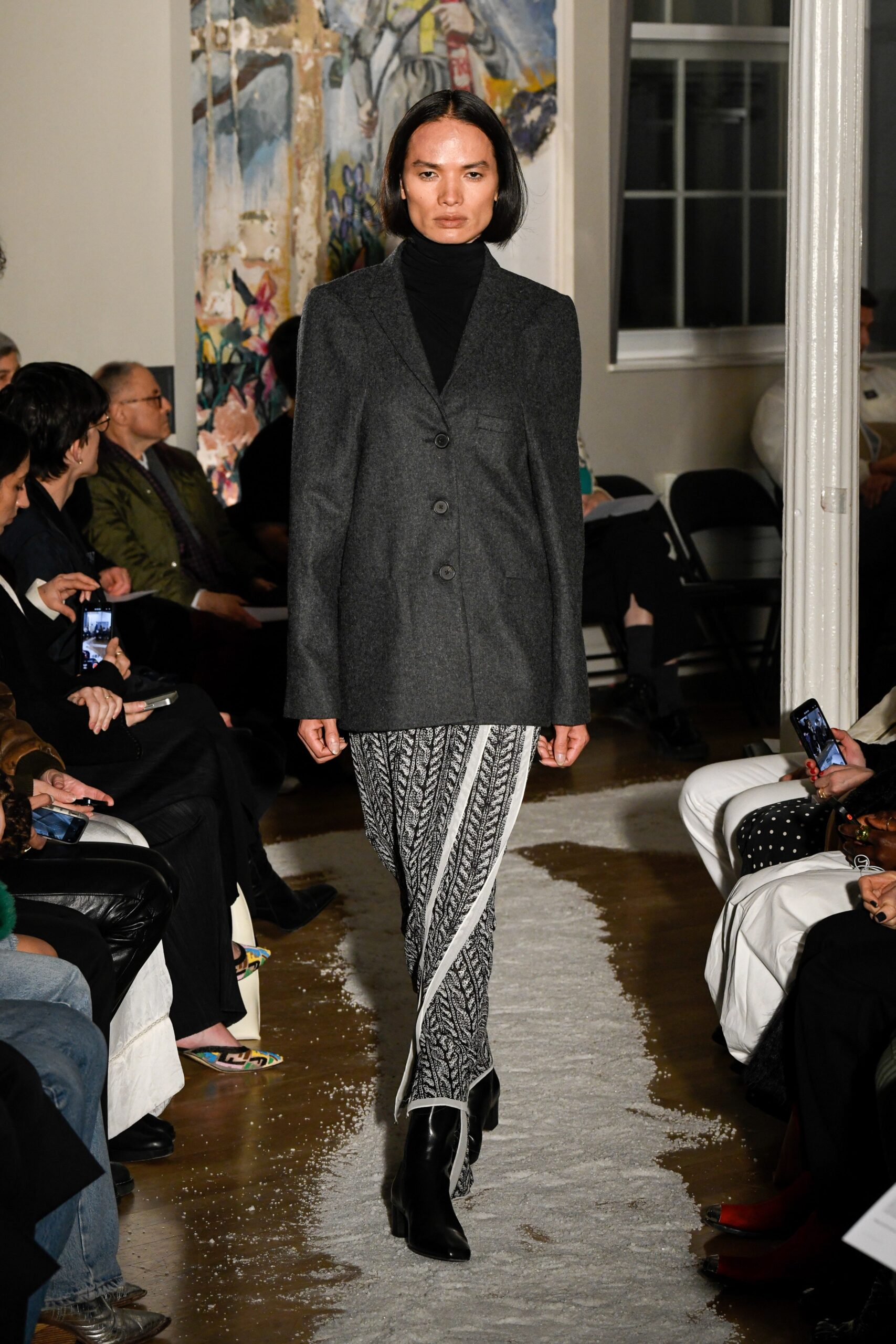 A fitted gray wool blazer with long sleeves, paired with striped straight-leg pants.