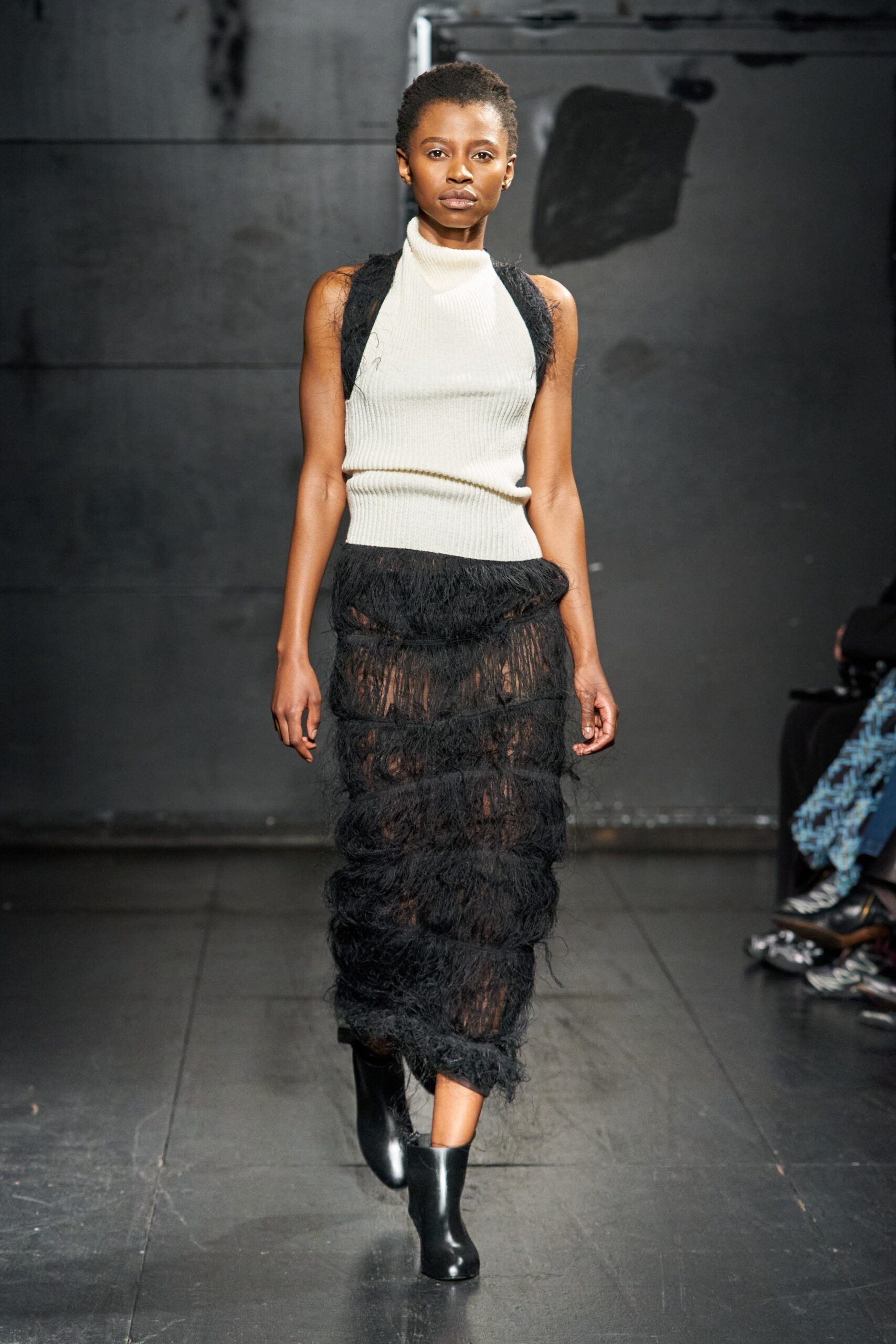 A fitted black and white sleeveless dress with a high neckline and tiered design.