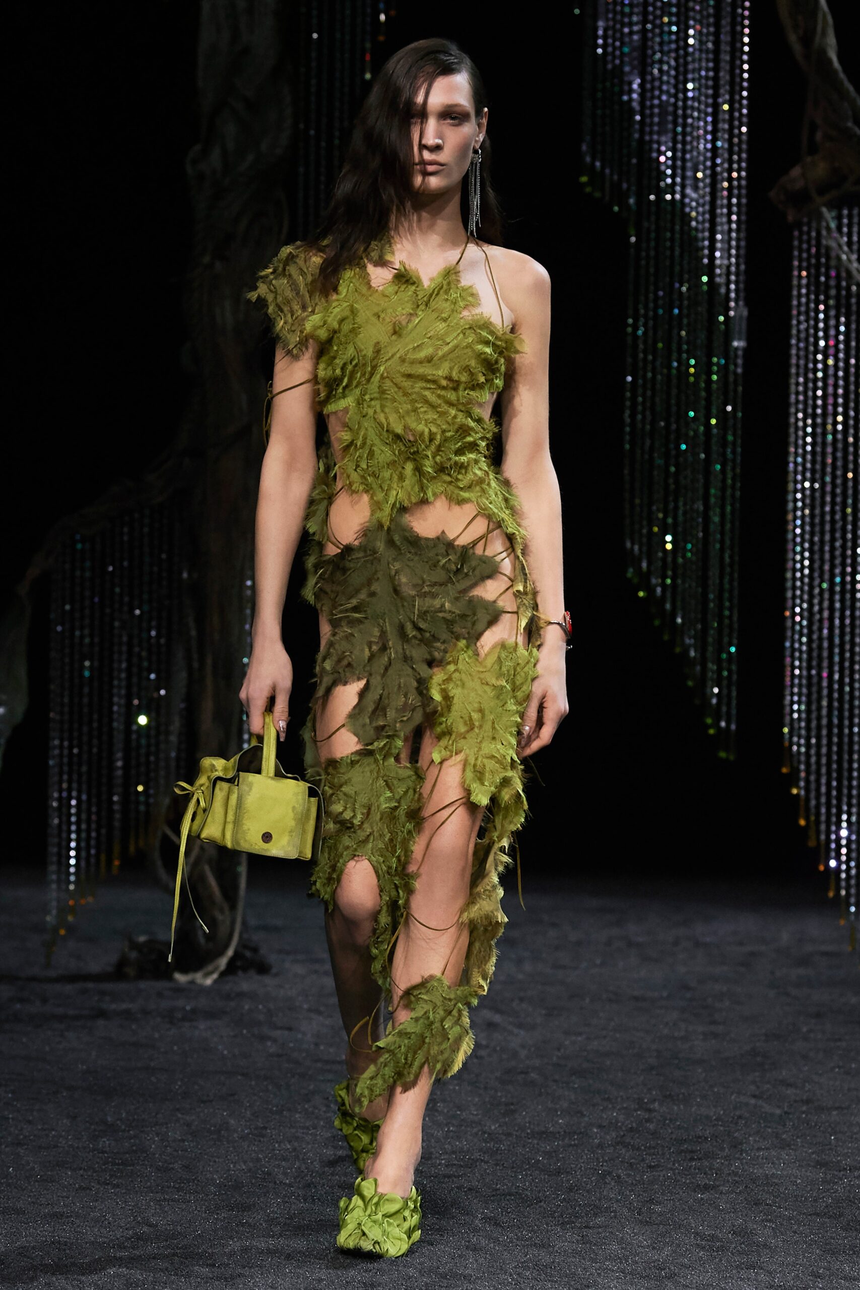 A fitted green dress with an asymmetric design and fringed details, featuring a sleeveless high-neck construction.
