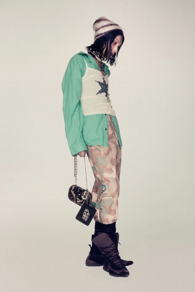 A relaxed green long-sleeve shirt layered over a tank top, paired with camouflage pants.