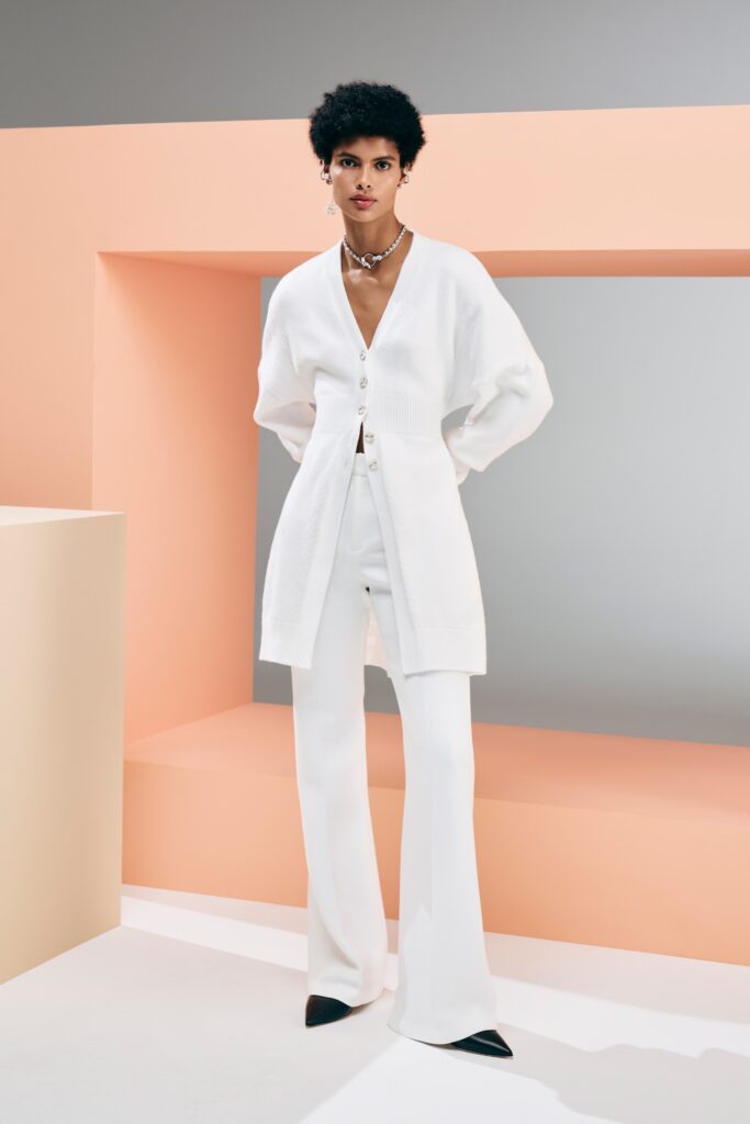 A fitted white blazer with long sleeves and collared neckline paired with straight-leg pants.