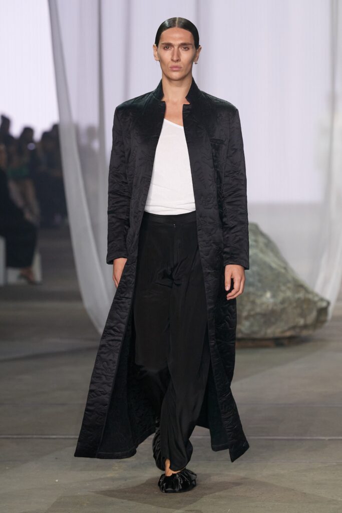 A relaxed black silk coat with a collared neckline paired with straight-leg pants.