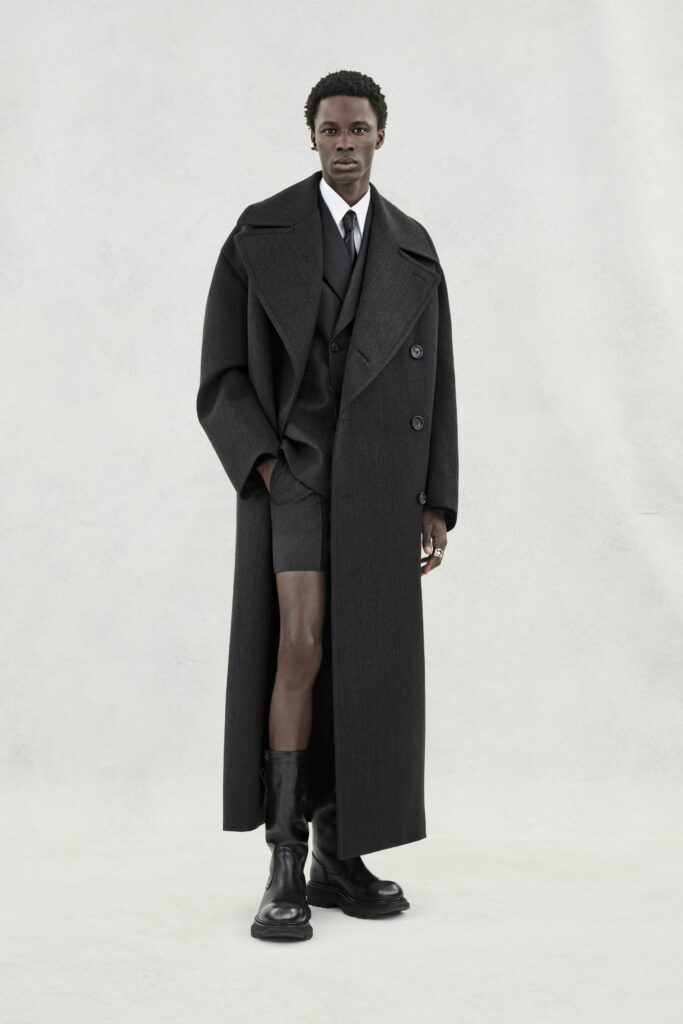 A structured black wool coat paired with a tailored suit, featuring a collared design.