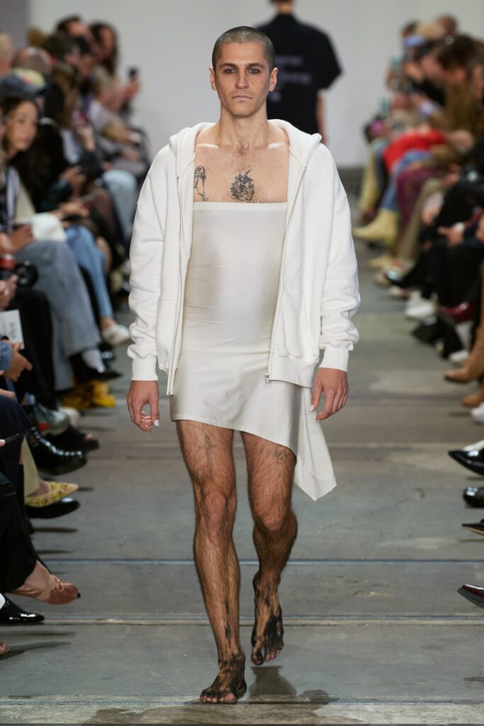 A fitted white sleeveless dress featuring a hood and an asymmetric design.