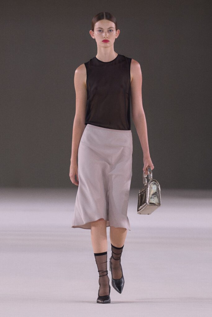 A fitted black silk sleeveless top paired with a beige asymmetric skirt.