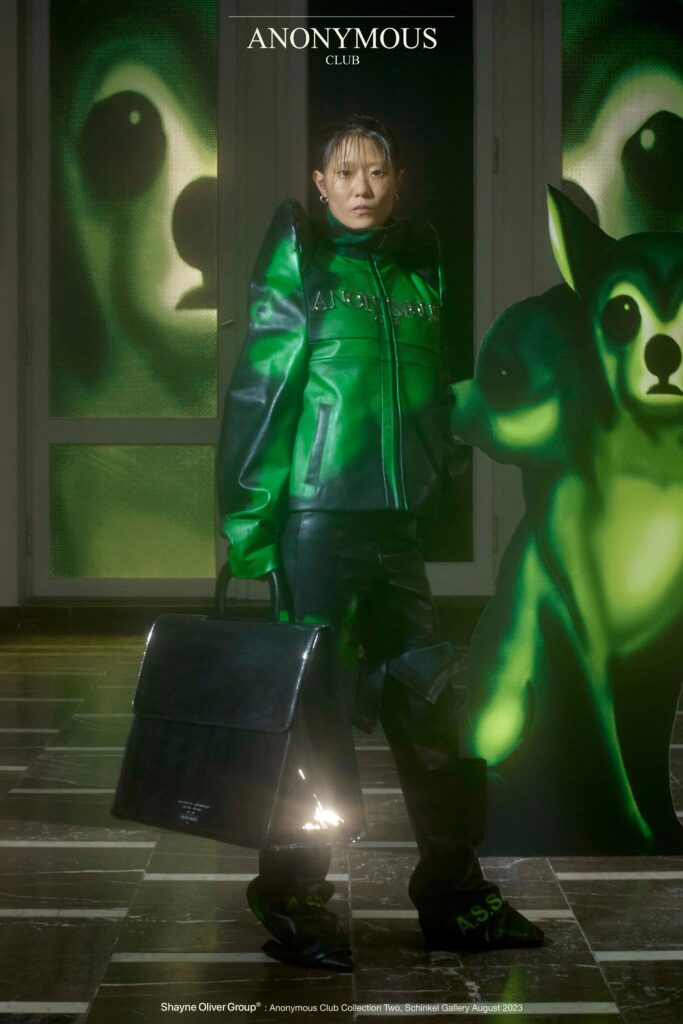 An oversized green leather jacket with long sleeves and a collared design, paired with black pants.