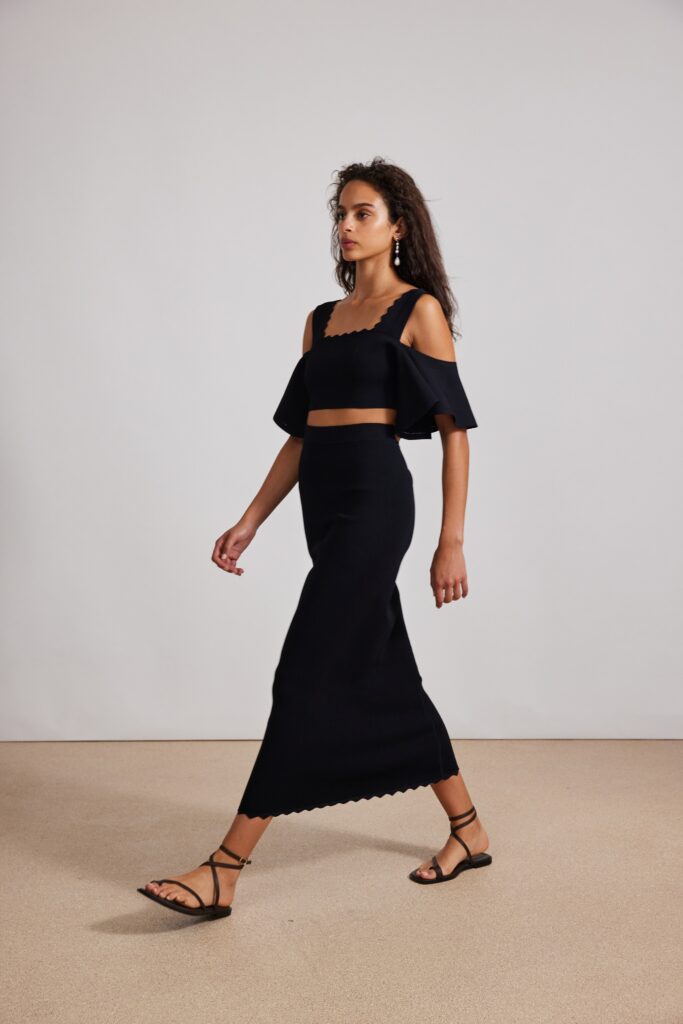 A fitted black cotton dress with a high neckline and tiered design details.