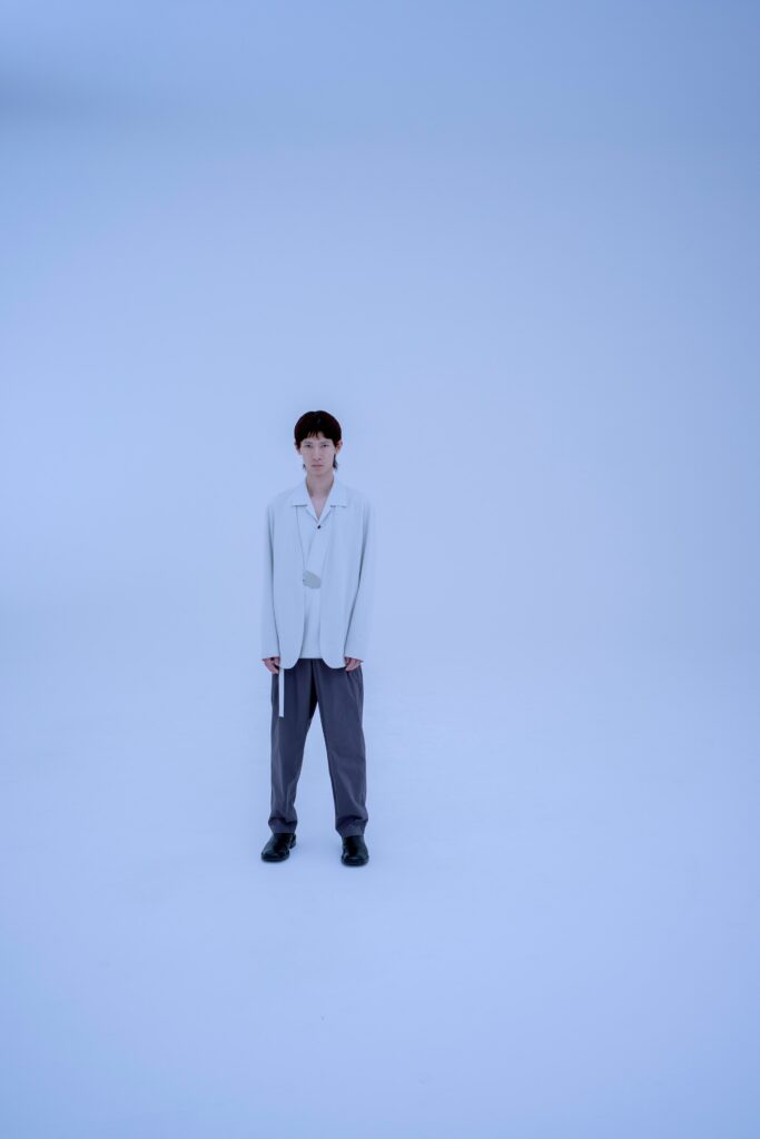 A relaxed white long-sleeve collared jacket paired with straight-leg gray pants.