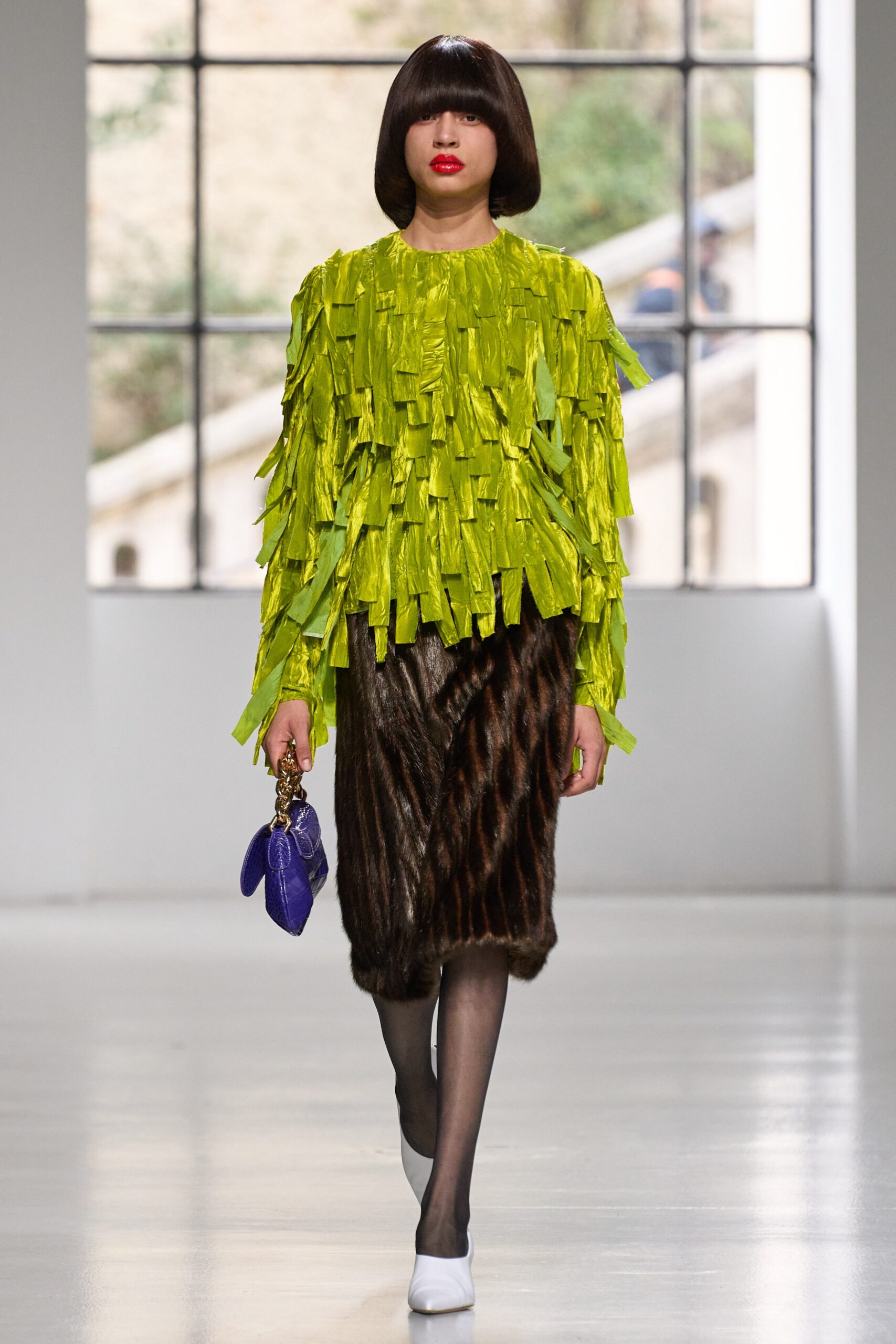 A fitted green fringed top with long sleeves paired with a brown fur skirt.