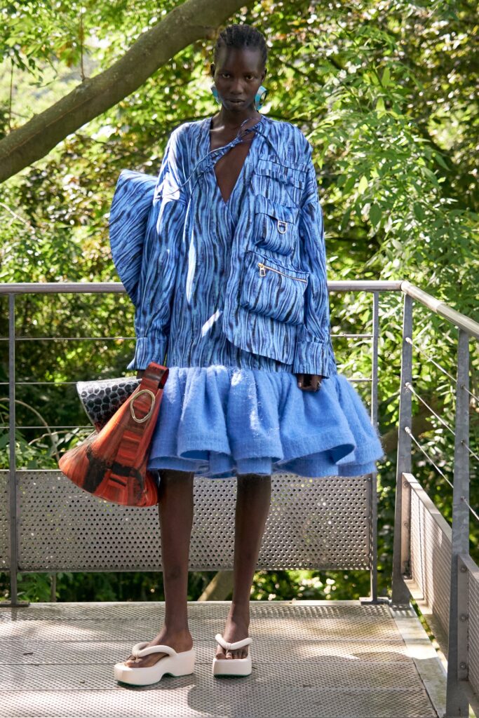 A relaxed blue cotton long-sleeve dress with a V-neckline and tiered silhouette.