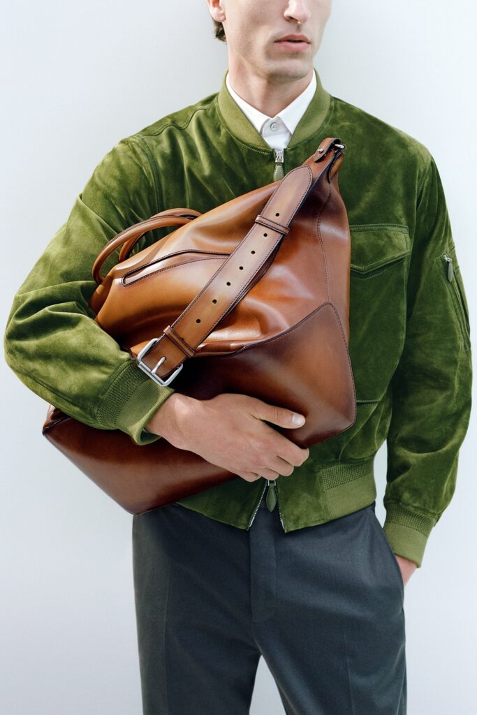 A relaxed green suede long-sleeve jacket paired with gray pants featuring a zippered detail.