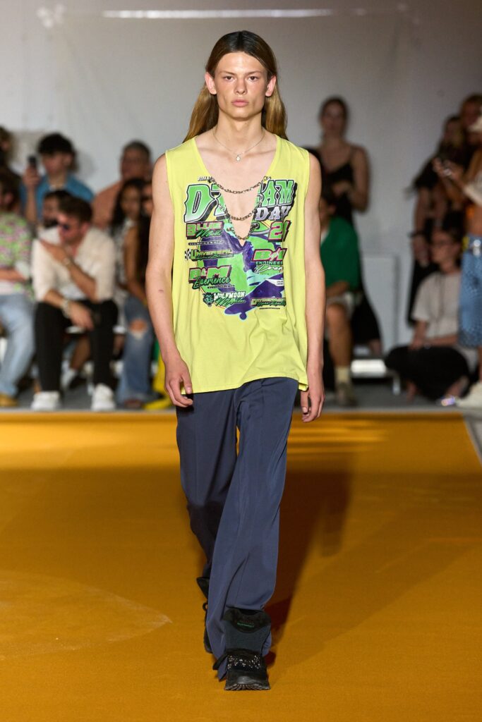 A relaxed yellow printed tank-top paired with blue pants for a casual look.
