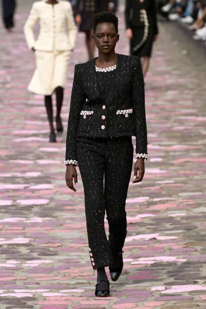 A tailored black tweed suit featuring long sleeves and button details.