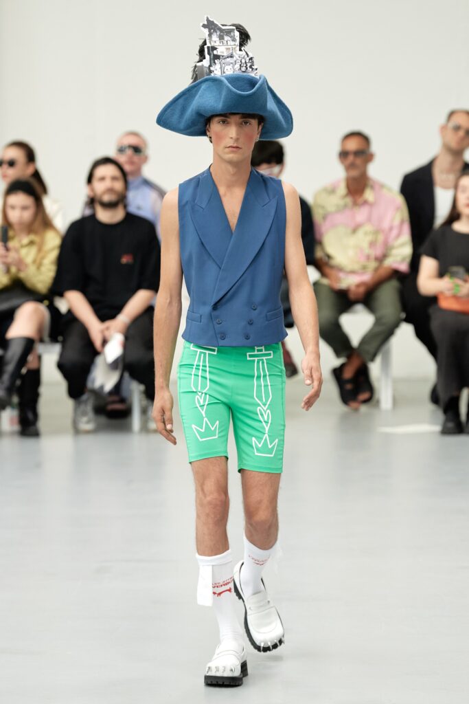 A fitted blue sleeveless vest with a collared design paired with green printed shorts.