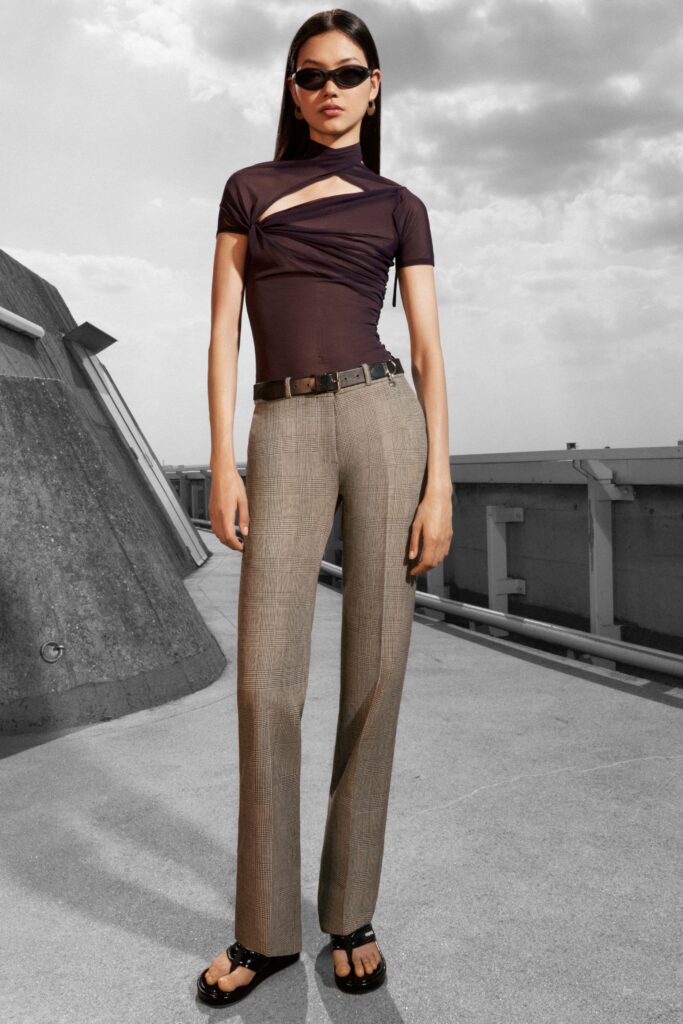 A fitted brown top with an asymmetric design paired with straight-leg pants.