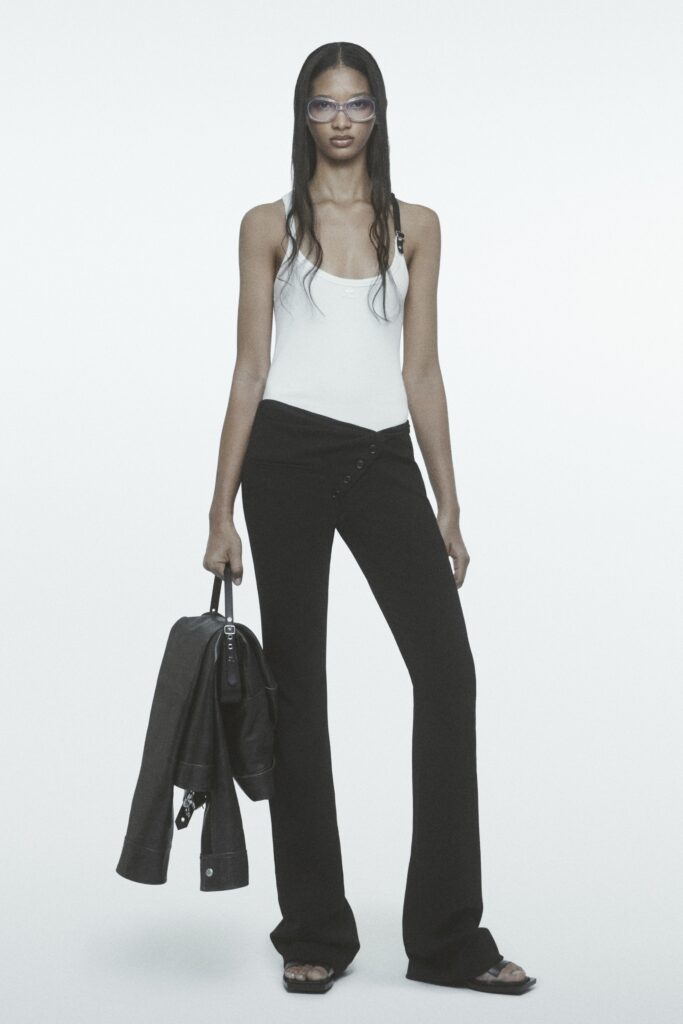 A fitted sleeveless white top paired with high-waisted black straight-leg pants.