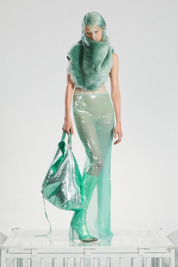 A fitted green sequined sleeveless top paired with high-neck pants featuring an asymmetric design.