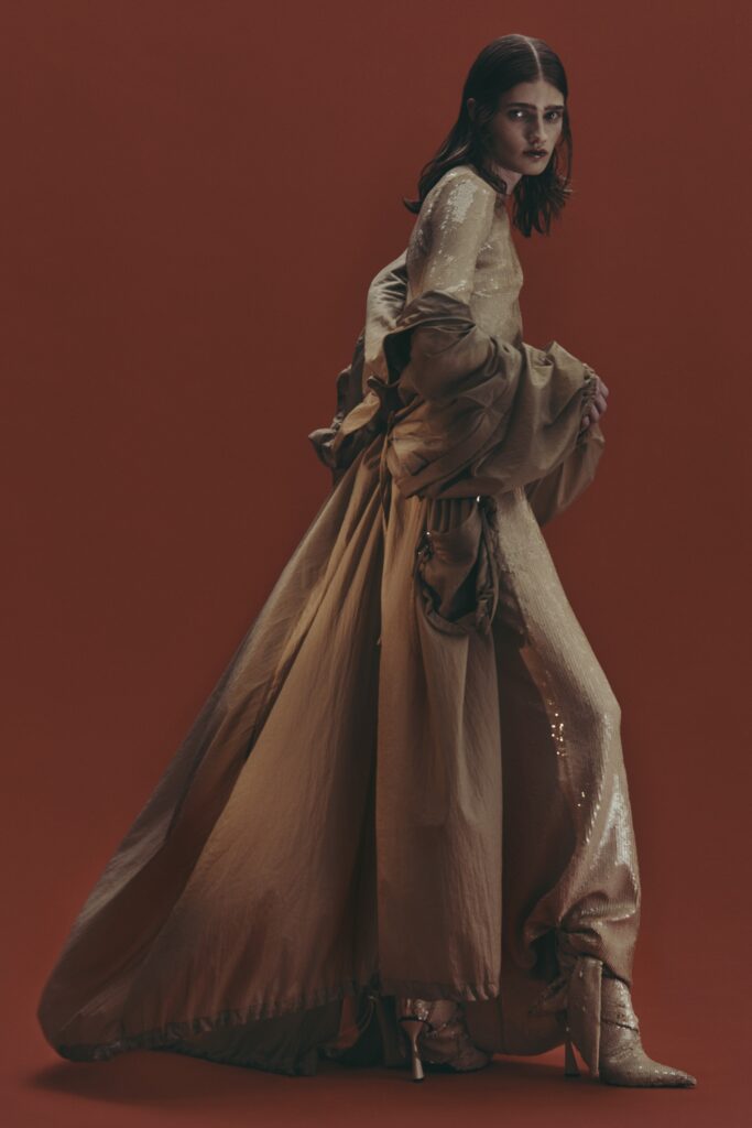 A relaxed gold silk dress with long sleeves and a high neckline featuring a draped design.