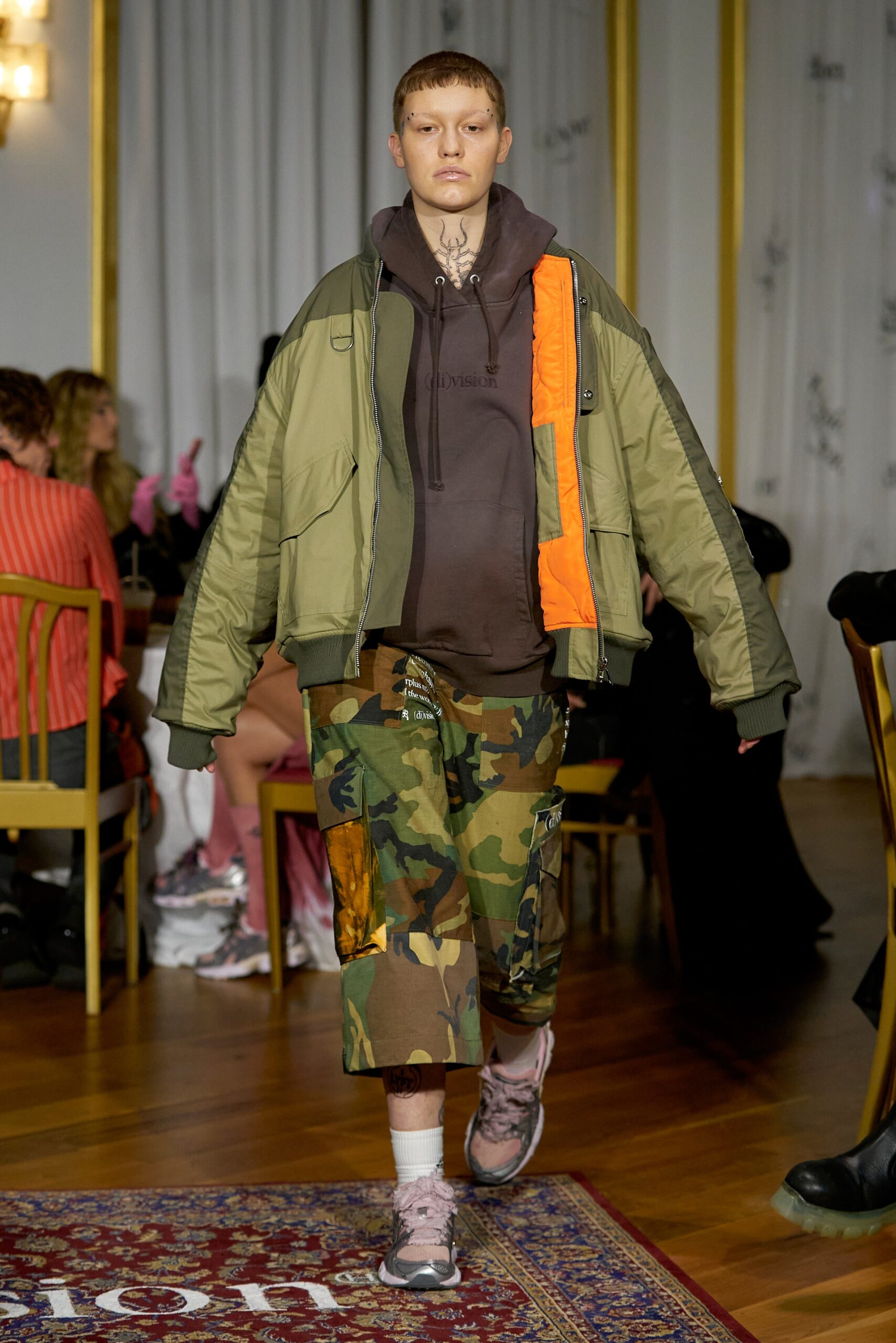 A relaxed green hooded jacket paired with camouflage pants for a casual look.
