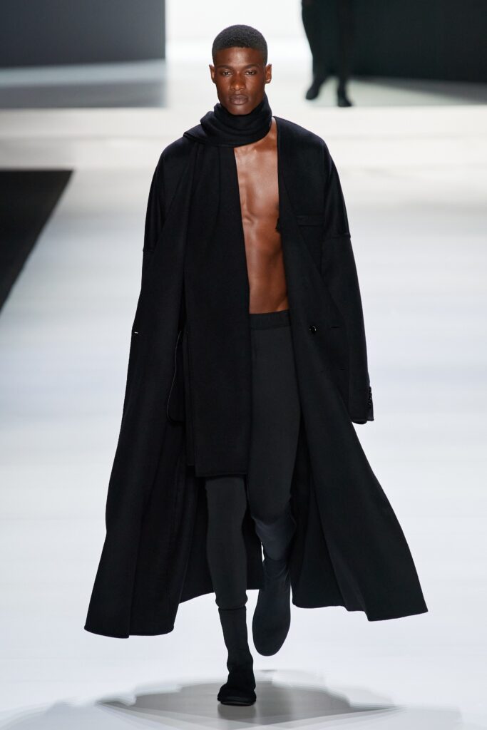 A relaxed black wool coat with long sleeves and an asymmetric design.