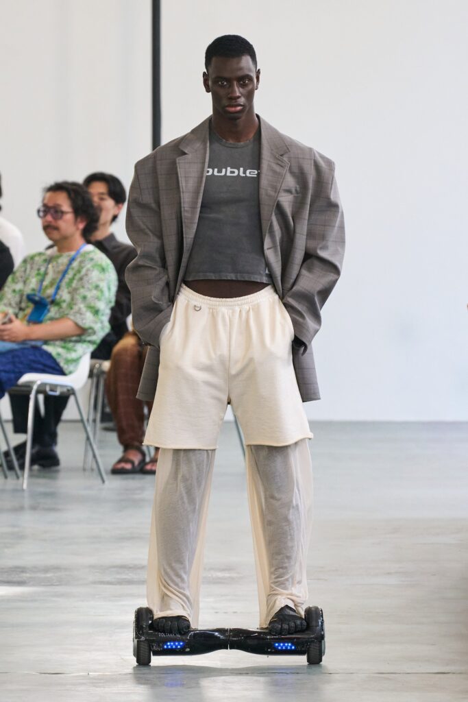 A relaxed gray jacket with long sleeves paired with beige pants, featuring an asymmetric design.