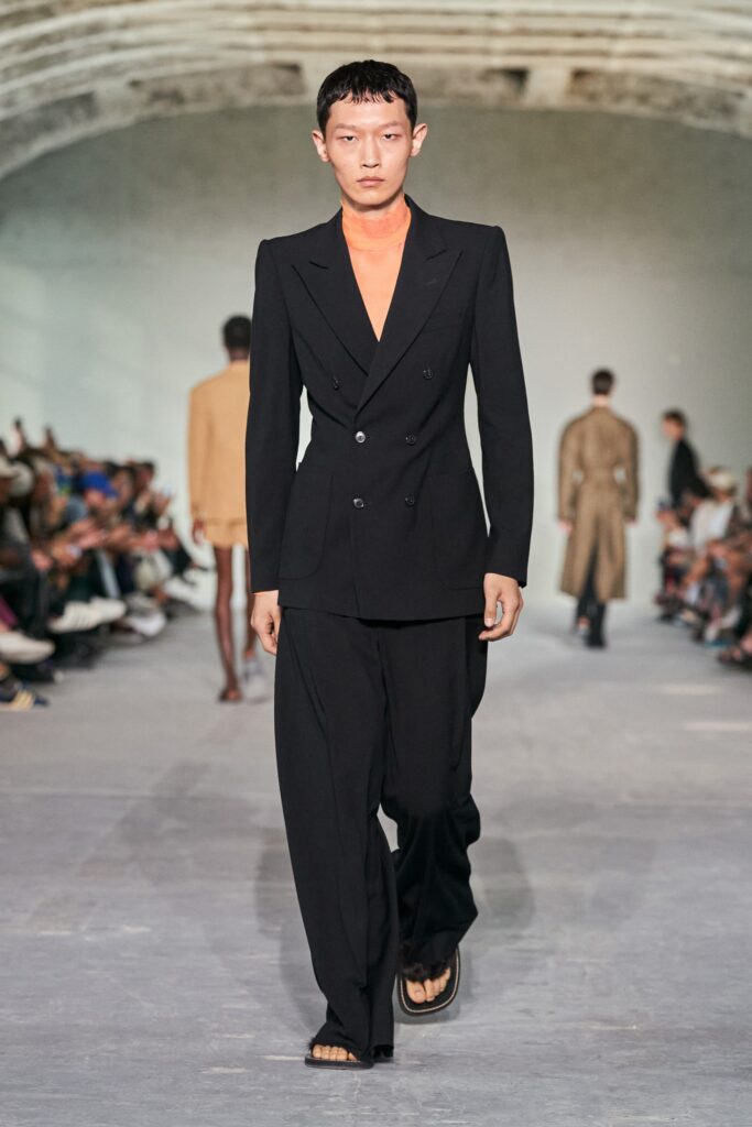 A tailored black suit with long sleeves, a collared shirt, and wide-leg trousers.
