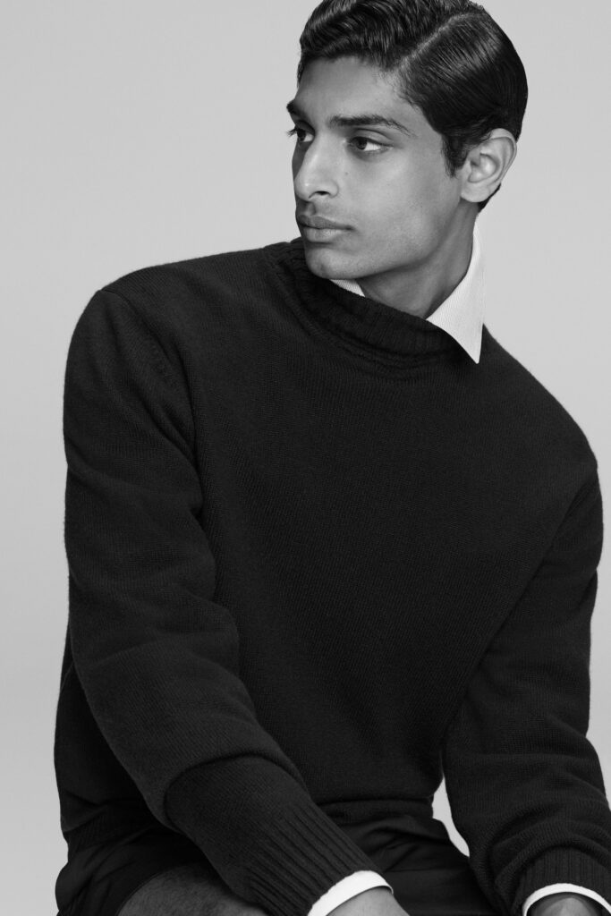A fitted black sweater layered over a white collared shirt with long sleeves.